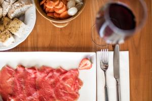 un tavolo con un piatto di carne e un bicchiere di vino di Agritur Calvola a Tenno