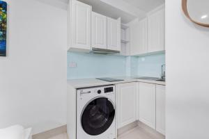 lavadero blanco con lavadora y secadora en Bright Studio Apartment in Surry Hills' Heart en Sídney