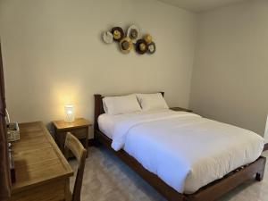 1 dormitorio con 1 cama, 2 mesas y reloj en The Old City Rooms, en Chiang Mai