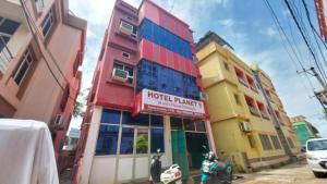 ein farbenfrohes Gebäude mit einem Hotelpalast auf einer Straße in der Unterkunft Hotel Planet 9 Puri - Wonderfull Stay with Family Near Sea Beach in Puri