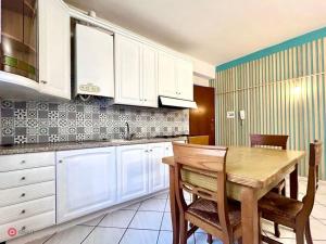 cocina con mesa de madera y armarios blancos en Appartamento centrale en Tortona