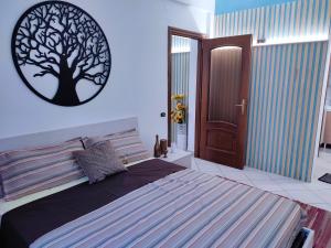 Appartamento centrale في تورتونا: غرفة نوم بسرير مع صورة شجرة على الحائط