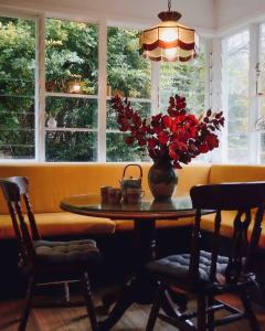 una mesa de comedor con un jarrón de flores. en Harrys House Warburton - Peaceful Riverside cottage in the perfect location, en Warburton
