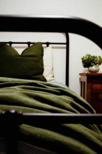 Una cama con una manta verde y una planta sobre una mesa en Harrys House Warburton - Peaceful Riverside cottage in the perfect location, en Warburton