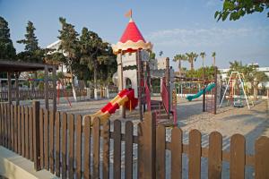 un parque infantil detrás de una valla con un tobogán en Atlantis Hotel en Cos