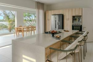 a kitchen with a large white island with bar chairs at Tamarin Sunset Beach VI in Tamarin +19 photos