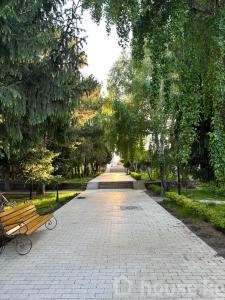 a walkway in a park with a bench and trees at Raduga West 'Emerald' Cottage in Koshkolʼ
