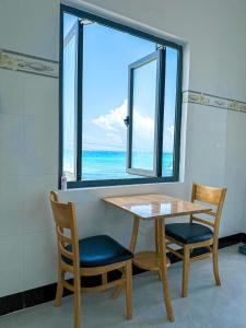 einen Tisch und zwei Stühle sowie ein Fenster mit Meerblick in der Unterkunft homestay Phúc Lũy in Cu Lao Thu