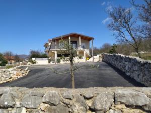 a house with a stone wall in front of a driveway at Apartmani Suzana in Crikvenica