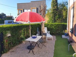 un tavolo con ombrellone rosso in un cortile di Chez Alain a Oye-Plage