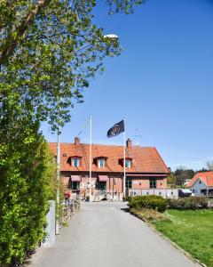a road in front of a house with a flag at Brösarps Gästgifveri & SPA in Brösarp