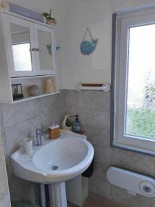 bagno con lavandino bianco e finestra di Chez Alain a Oye-Plage