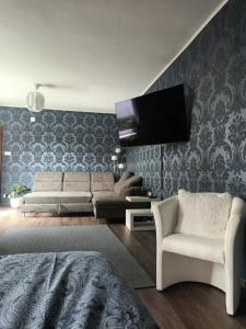 a living room with a couch and a tv on a wall at The Cottage in Murska Sobota