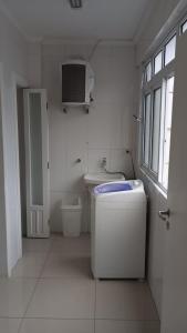La salle de bains blanche est pourvue de toilettes et d'une fenêtre. dans l'établissement Guaruja Praia de Pitangueiras frente ao mar, à Guarujá