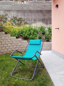 una silla azul sentada en el césped junto a una pared en Casa Contessa lago Maggiore, en Caravate