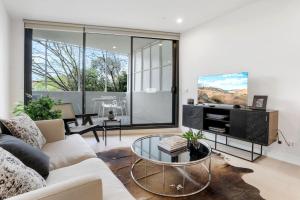 a living room with a couch and a glass table at Modern Apartment Overlooking Leafy Ivanhoe in Melbourne