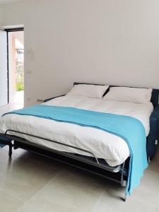 Una cama con una manta azul encima. en Casa Contessa lago Maggiore, en Caravate