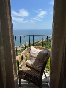 een rieten stoel op een balkon met uitzicht op de oceaan bij LA CASA SUL MARE in San Vito Chietino