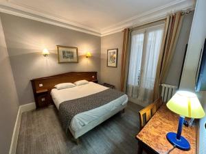 a bedroom with a bed and a table with a lamp at Hotel Richmond Gare du Nord in Paris