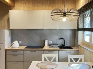a kitchen with white cabinets and a sink and a table at Holiday house in Pobierowo for 8 people near the sea in Pobierowo