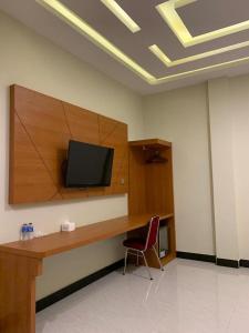 a room with a desk with a television on a wall at BLESS HOTELS in Sintang