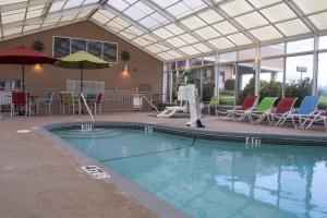 a swimming pool with chairs and umbrellas in a building at Lamplighter Inn and Suites - North in Springfield