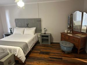 sypialnia z łóżkiem, komodą i lustrem w obiekcie Oudam Overnight Accomodation w mieście Bloemfontein
