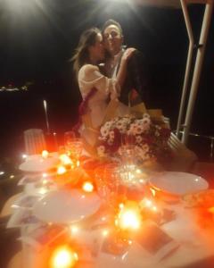 a bride and groom kissing in front of a table with lights at cesme yat isletmeciligi in Çeşme