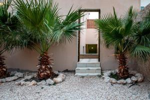 un patio con 2 palmeras frente a un edificio en Elegant Garden & 2Living Areas, 2 Bed Rooms for 6 Guests, en Umm al ‘Amad