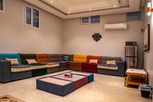 una sala de estar con sofás coloridos y una mesa. en Elegant Garden & 2Living Areas, 2 Bed Rooms for 6 Guests en Umm al ‘Amad