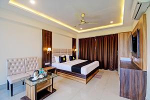 una camera d'albergo con letto, divano e TV di OYO Palette - The Grand Aryans Hotel a Calcutta
