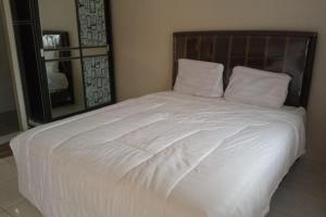 Una cama con sábanas blancas y almohadas en un dormitorio en OYO 93850 Njy House Syariah en Pekanbaru