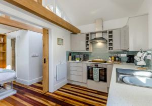uma cozinha com armários brancos e um lavatório em Y Nyth em Cerrig-y-Druidion