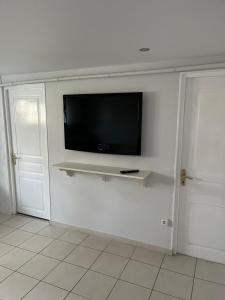 - une télévision à écran plat sur un mur blanc dans l'établissement Bel appartement de 60 m2, à Rosières-près-Troyes
