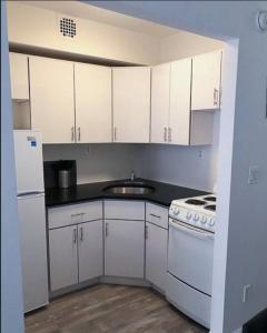 eine kleine Küche mit weißen Schränken und einem Waschbecken in der Unterkunft Cozy Studio! Upper East Side! in New York