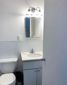 ein Badezimmer mit einem WC, einem Waschbecken und einem Spiegel in der Unterkunft Cozy Studio! Upper East Side! in New York