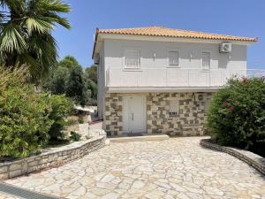 a large white house with a stone driveway at Luxurious Villa in Peloponnese with Swimming Pool in Kamária