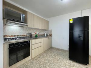a kitchen with a black refrigerator and a stove at Medellin Tu hogar en la eterna primavera in Medellín