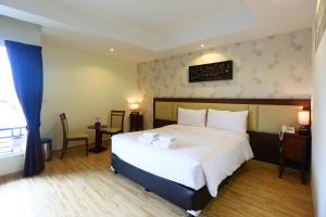 una camera da letto con un grande letto bianco e una finestra di Suvarnabhumi Ville Airport Hotel a Lat Krabang