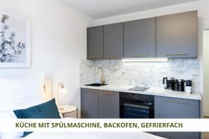 La cuisine est équipée de placards gris et d'un four avec plaques de cuisson. dans l'établissement Apartment Wahnfried No5 - zentrales Cityapartment Küche mit Duschbad - 300m zur Fussgängerzone, à Bayreuth