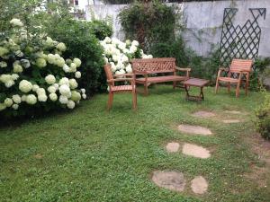 duas cadeiras e um banco num quintal com flores em Saint-Jean de Luz, Centre, Maison 8 couchages - classée 3* em Sainte-Barbe