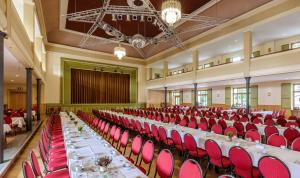 a banquet hall with long tables and red chairs at Flair Hotel Kamenz in Kamenz