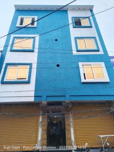 a blue building with many windows on it at Hotel Santosh Inn Puri - Jagannath Temple - Lift Available - Fully Air Conditioned in Puri