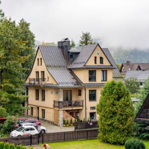 a large house with a car parked in front of it at Szarotka in Zakopane