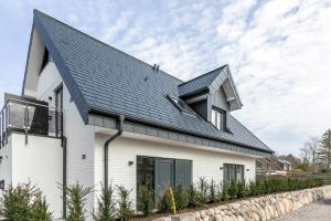 une maison blanche avec un toit noir dans l'établissement Horst Wai Hues, à Westerland