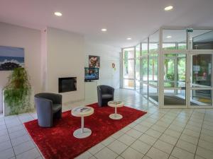 a lobby with two chairs and two tables on a red rug at Holiday home Club Le Domaine Du Golf 2 in Saint-Hilaire-Saint-Florent