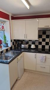 uma cozinha com armários brancos e um lavatório em 3 Cosy private rooms in house near Safari Park & Hospital 