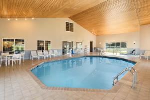 a large swimming pool in a large room with tables and chairs at Country Inn & Suites by Radisson, Chippewa Falls, WI in Chippewa Falls