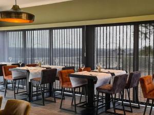 ein Esszimmer mit Tischen und Stühlen und großen Fenstern in der Unterkunft Villa in France with Private Garden in Lanzac