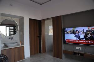 a bathroom with a tv and a sink and a mirror at Gulmohar Homes in Udaipur
